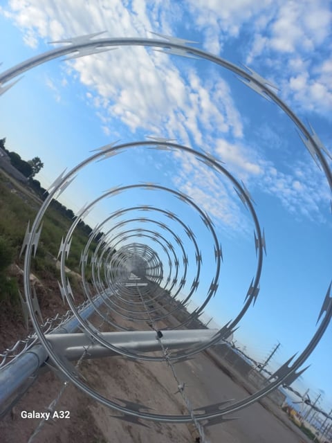 Perspective view through stacked metal spiral hoops with blue sky and clouds in background